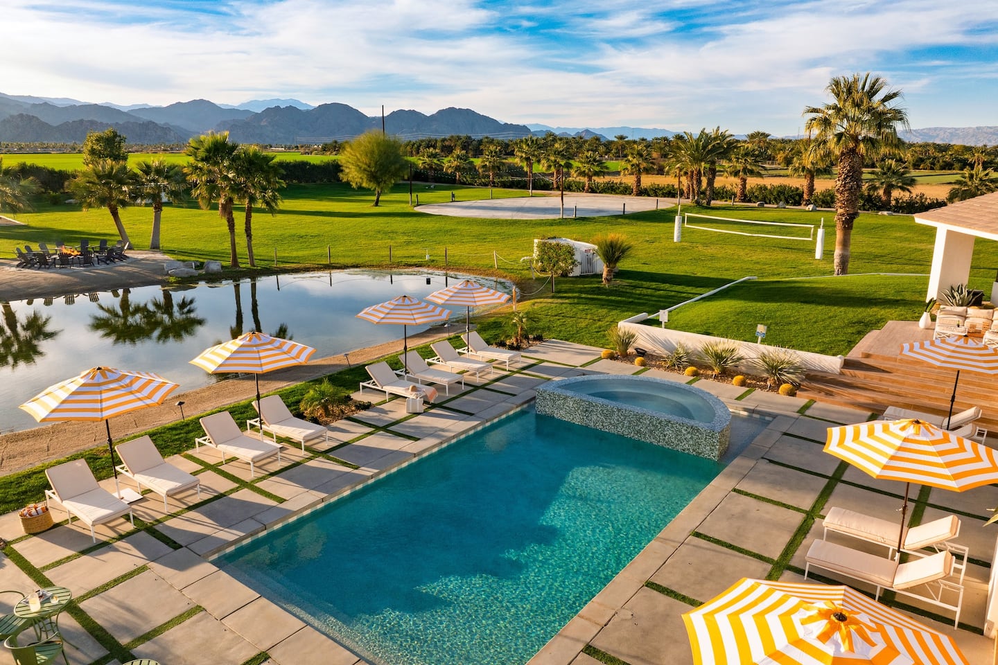 Pool and spa with sun loungers, striped umbrellas, and mountain views