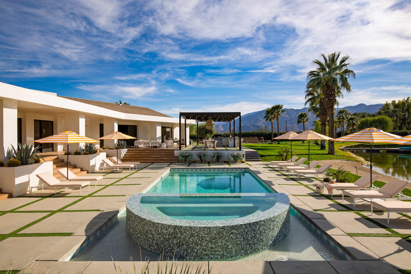 The villa and pool in the desert sun with palms and mountains