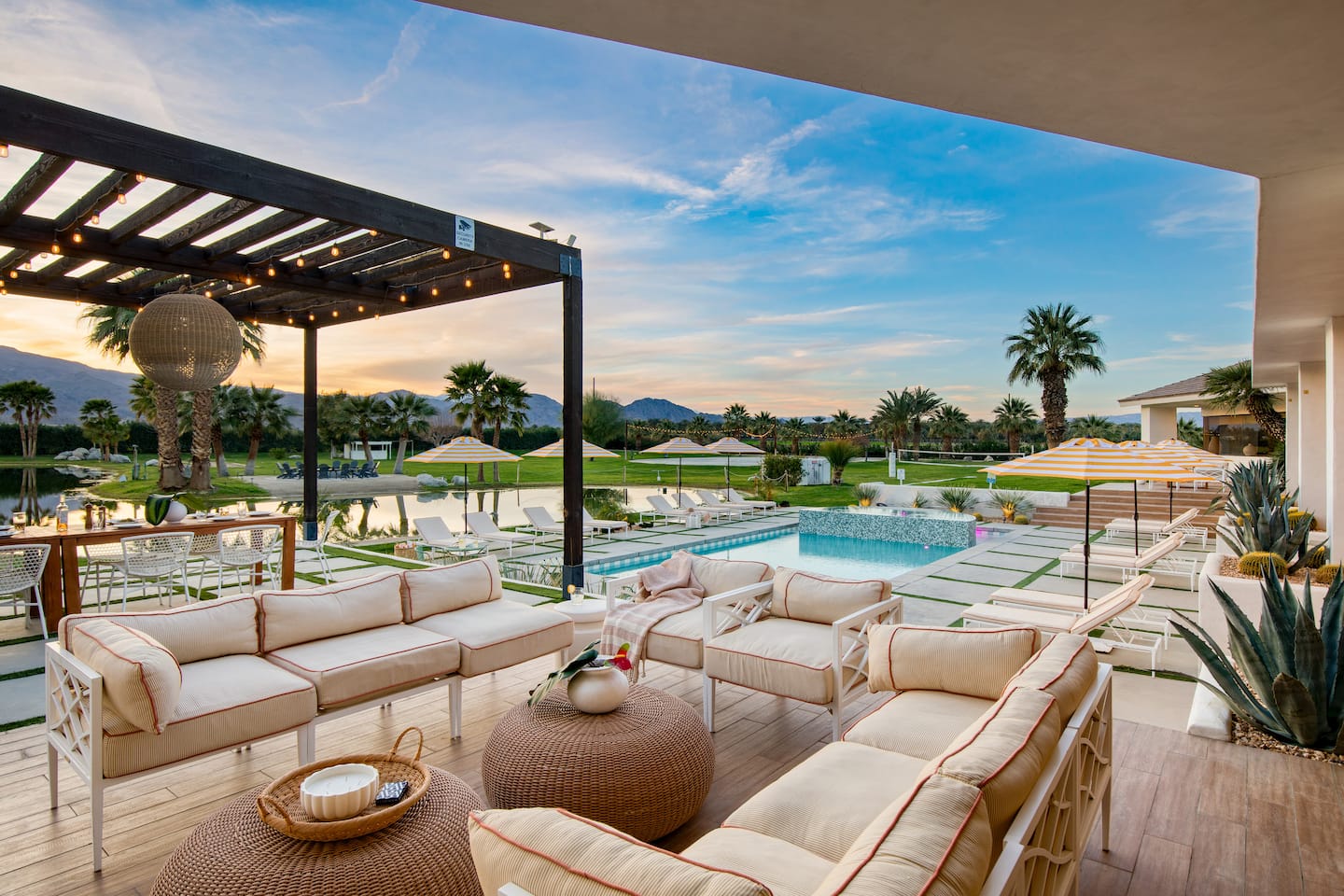 Poolside lounge with palms and mountains at sunset